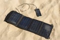 Portable solar panel is on the beach charges mobile phone.