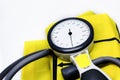 A portable sphygmomanometer resting on a yellow cuff. Instrument for measuring blood pressure