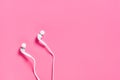 Portable white headphones for smartphone or audio player on pink