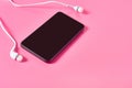 Portable white headphones and smartphone or tablet on pink background