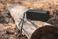 Portable wireless bluetooth speaker for listening to music on a log in the forest Royalty Free Stock Photo