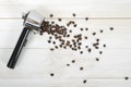 Portafilter handle with scattered coffee beans on wooden surface in top view