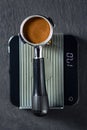 Portafilter on the scales with freshly ground morning coffee on grey background