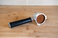 Portafilter with temping ground coffee on wooden table Royalty Free Stock Photo