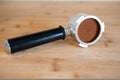 Portafilter with temping ground coffee on wooden table Royalty Free Stock Photo