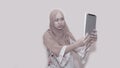 Portait of asian muslim woman wearing head scarf or hijab playing with tablet pc