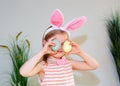 Blond child girl wearing bunny ears on Easter day play with Easter eggs at home
