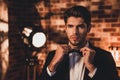 Portait of confident handsome man corecting his bow tie and wearing for event party