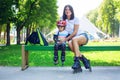 Portait of cute baby boy and his mom wearing inline skates sitting on bench. Royalty Free Stock Photo