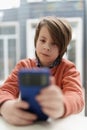 Portait of cute little boy using modern smart phone. White kid browsing app on mobile phone in a restaurant Royalty Free Stock Photo