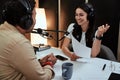 Portait of happy female radio host smiling, talking to male guest, presenter while moderating a live show in studio Royalty Free Stock Photo