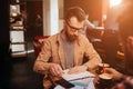 A portait of serious businessman sitting in front of his partner in small and cozy cafe. He is studying information that