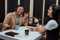 Portait of two cheerful radio hosts, man and woman smiling, pointing at each other, while moderating a live show in Royalty Free Stock Photo