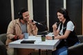 Portait of two happy radio hosts, man and woman smiling while talking with each other, moderating a live show in studio Royalty Free Stock Photo