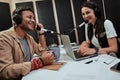 Portait of two happy radio hosts, young man and woman talking with each other while moderating a live show in studio Royalty Free Stock Photo