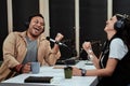 Portait of two radio hosts, man and woman laughing while talking with each other, moderating a live show in studio Royalty Free Stock Photo