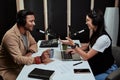 Portait of two radio hosts, young man and woman talking with each other while moderating a live show in studio Royalty Free Stock Photo