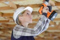 Portait young woman drilling ceiling