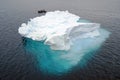 Ice is white above the water surface  but blue below the water surface. There is a small boat behind the ice floes. Royalty Free Stock Photo