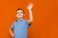 Portarait of caucasian happy smiling little boy with raised hand on orange wall Royalty Free Stock Photo