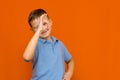 Portarait of caucasian happy smiling little boy with raised hand on orange wall Royalty Free Stock Photo