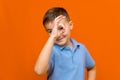 Portarait of caucasian happy smiling little boy with raised hand on orange wall Royalty Free Stock Photo