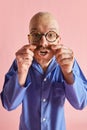 Portarit of funny man in pajama looking at camera and straightensand curls mustaches over pastel rose background.