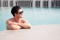 Portarit handsome, muscular caucasian white man wearing sunglasses in a swimming pool summer vacation