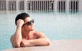 Portarit handsome, muscular caucasian white man wearing sunglasses in a swimming pool summer vacation