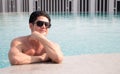 Portarit handsome, muscular caucasian white man wearing sunglasses in a swimming pool summer vacation