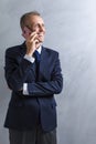 Portarit of Smiling Caucasian Man in Blue Suit Speaking on Cellphone. Posing Against Grunge Wall