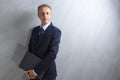 Portarit of Young Caucasian Man in Blue Suit Posing with Laptop Against Grunge Wall