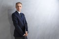 Portarit of Young Caucasian Man in Blue Suit Posing with Laptop Against Grunge Wall