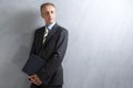 Portarit of Young Caucasian Man in Grey Suit Posing with Laptop Against Grunge Wall