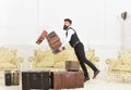 Porter, butler accidentally stumbled, dropping pile of vintage suitcases. Baggage insurance concept. Man with beard and Royalty Free Stock Photo