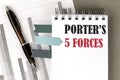 Porter\'s 5 Forces text on notebook with pen, calculator and chart on a grey background Royalty Free Stock Photo