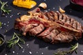 Porterhouse t-bone steak is grilled sliced on a piece with grilled corn, sauce, chilli, rosemary, salt, garlic on black background Royalty Free Stock Photo