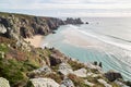 Porthcurno, Cornwall, UK - Top view of Pedn Vounder Beach with Logan Rock and ocean on a sunny day