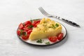 Portion of baked polenta with cheese on a white plate with parsley and cherry tomatoes on a light gray background