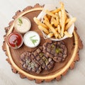 Portion of BBQ beef filet mignon with sauces and fried potatoes