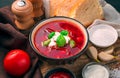 A portion of borscht with sour cream close-up, bread, tomato and tomato sauce on a wooden background Royalty Free Stock Photo