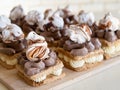 Portion cakes of meringue and cocoa butter cream in square form on a wooden stand, a piece of cake on a light wooden background.