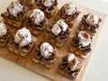 Portion cakes of meringue and cocoa butter cream in square form on a wooden stand, a piece of cake on a light wooden background.