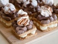 Portion cakes of meringue and cocoa butter cream in square form on a wooden stand, a piece of cake on a light wooden background.