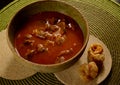 A portion of chicken gizzards, braised and cooked in tomato sauce, in a green bowl, on top of two round, clear ceramic bases and a