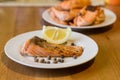 Portion of cooked salmon fillet with lemon slice on white plate