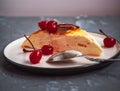 Portion of cottage cheese casserole on a ceramic saucer with canned cherries filmed from close range Royalty Free Stock Photo