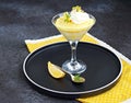 Portion creamy dessert with lemon curd, mascarpone cream and biscuit, garnished with whipped cream and crushed pistachios, in