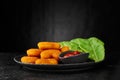 Portion of crispy golden fried nuggets in a plate with sauce and lettuce. Copy space. Dark mood. Low angle view Royalty Free Stock Photo