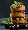 Portion crumble pie with cherries on a wooden board decorated with green mint leaves